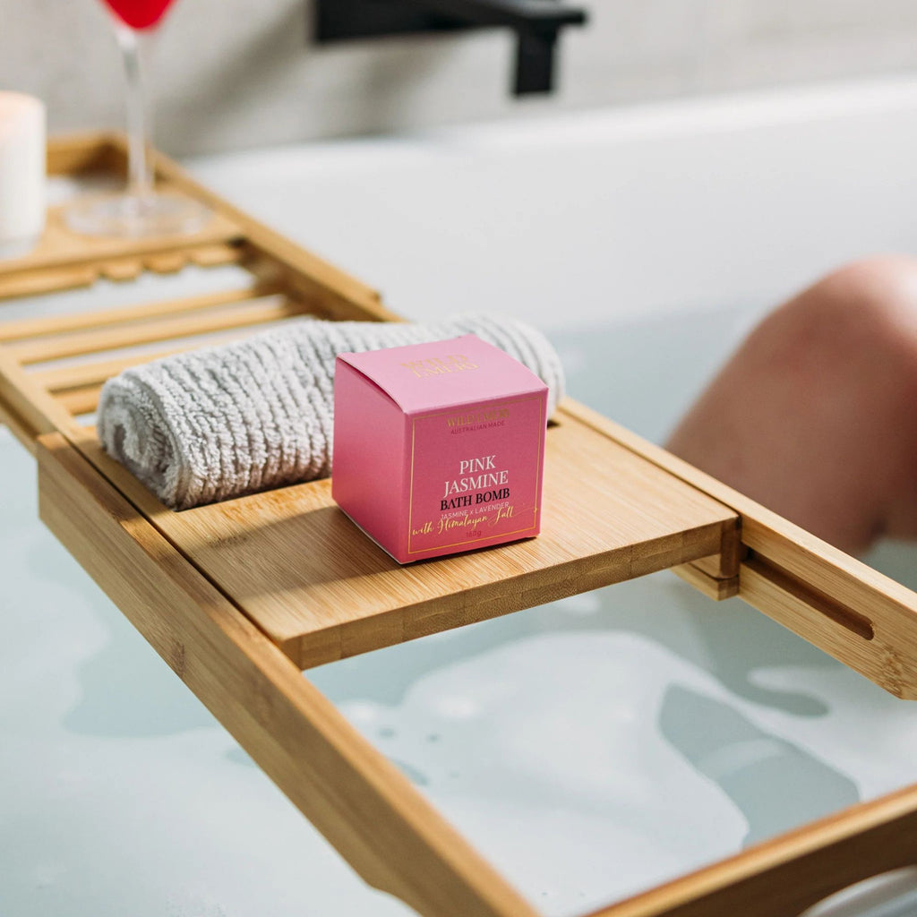 Bath Bomb - Pink Jasmine by Wild Emery. A pink box on a wooden tray shelf over a bathrub