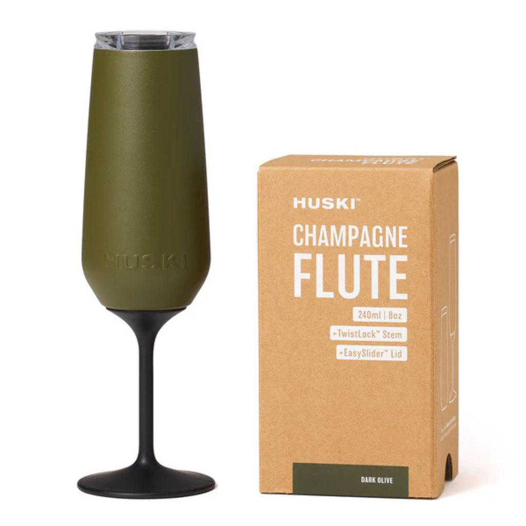 Champagne flute in an olive green colour with black stem. Next to packaging box against a white background