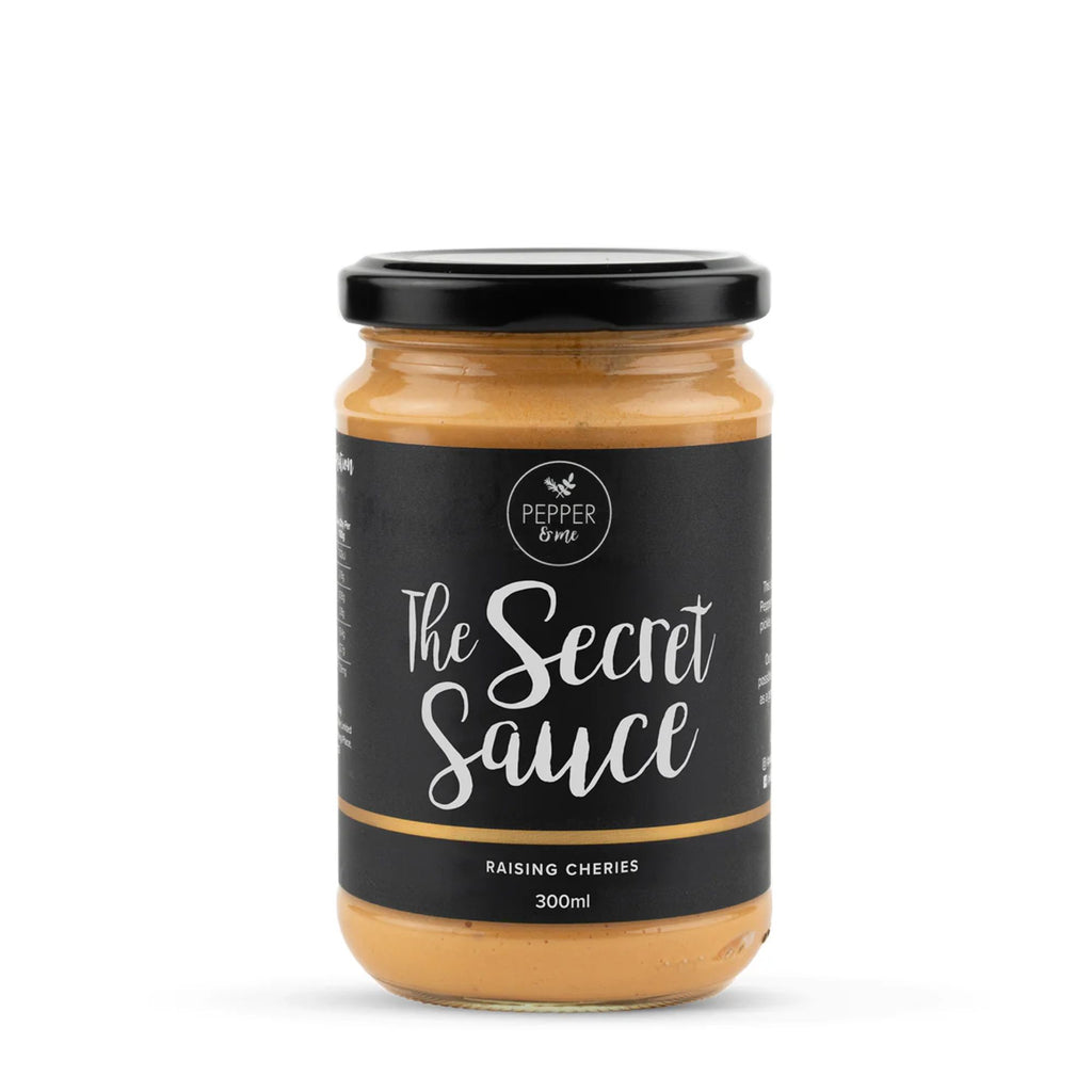 Jar of orange sauce with a black lid and label, labelled "Pepper & Me the secret sauce"