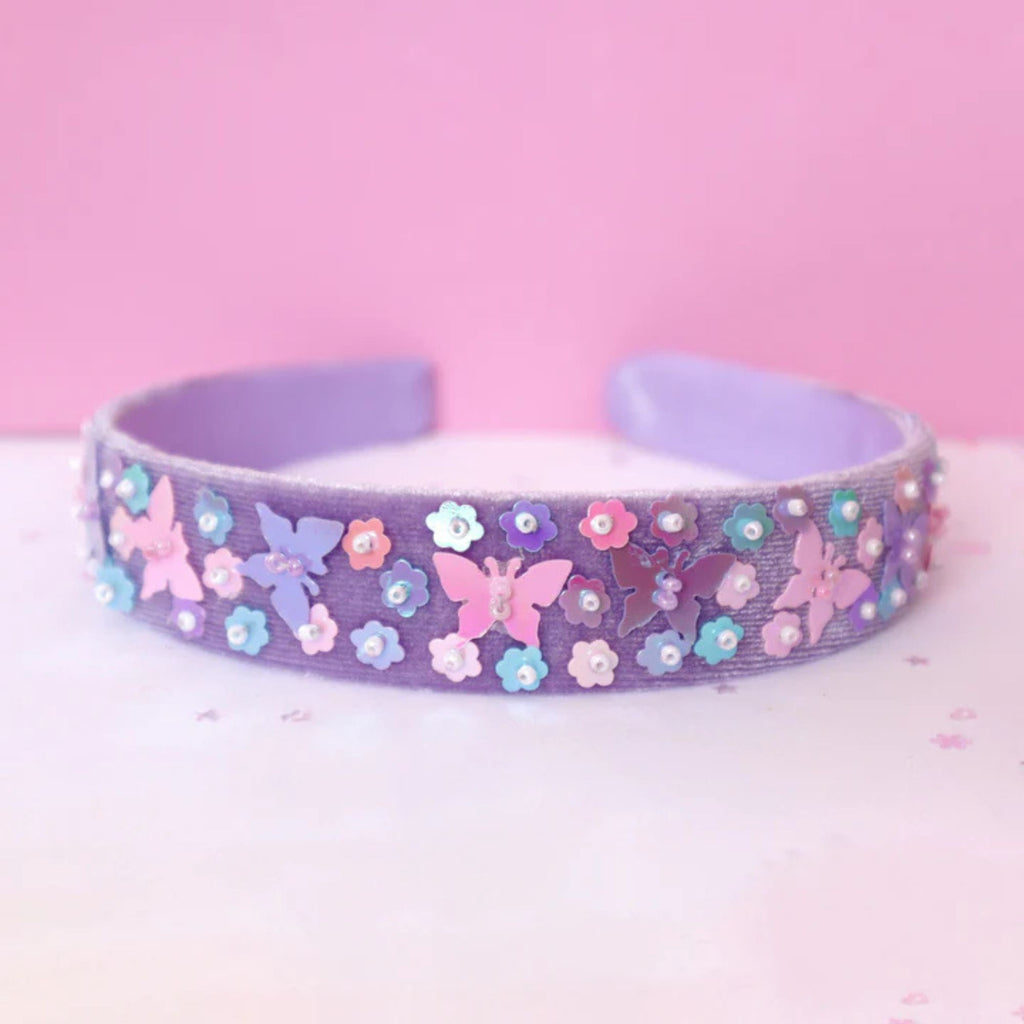 childrens purple butterfly headband with sparkly sequins. Against a pink background