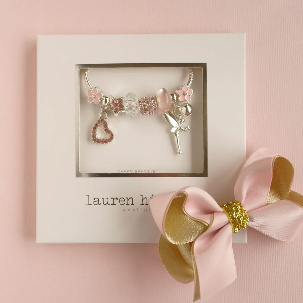 chilren's fairy charm bracelet in silver and pink, in a white box with a pink and gold bow attached. Against a pink background