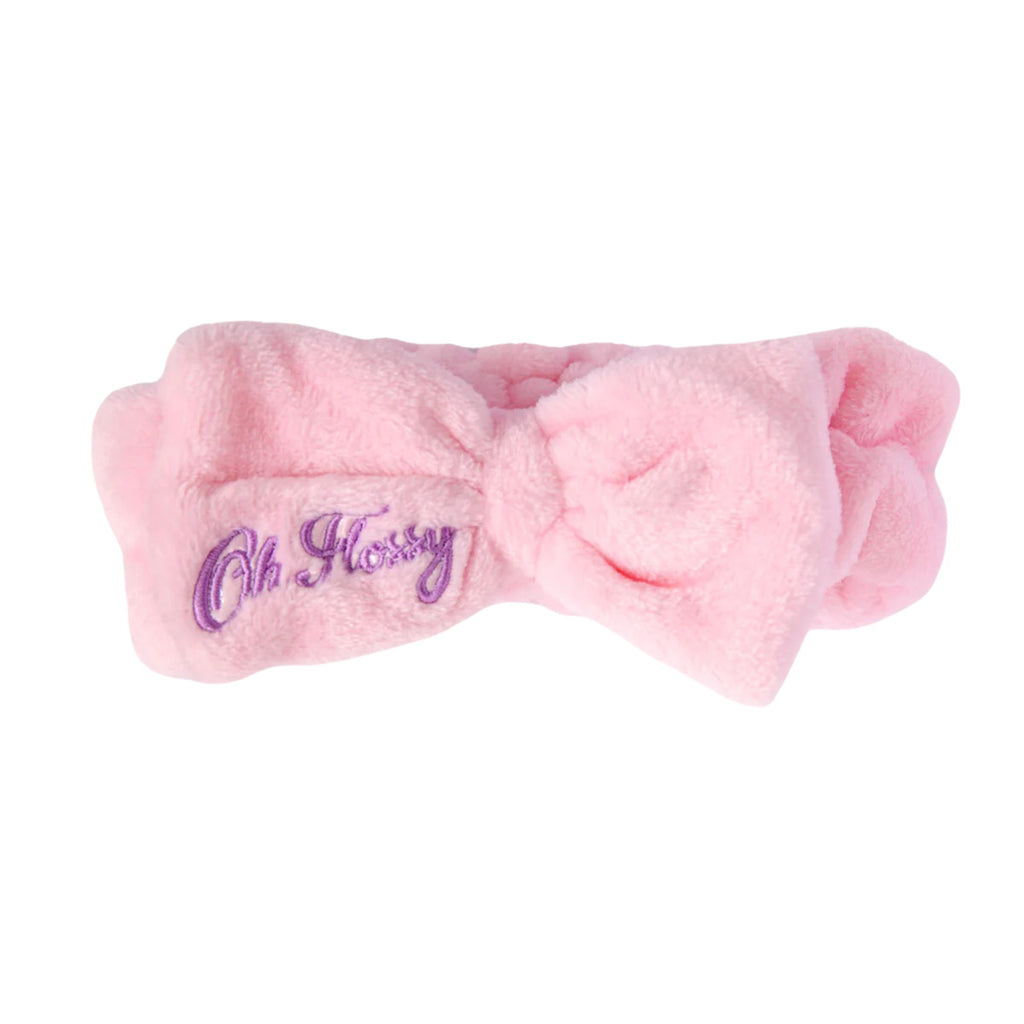 Fluffy pink cosmetic headband with pink bow and purple logo. On a white background