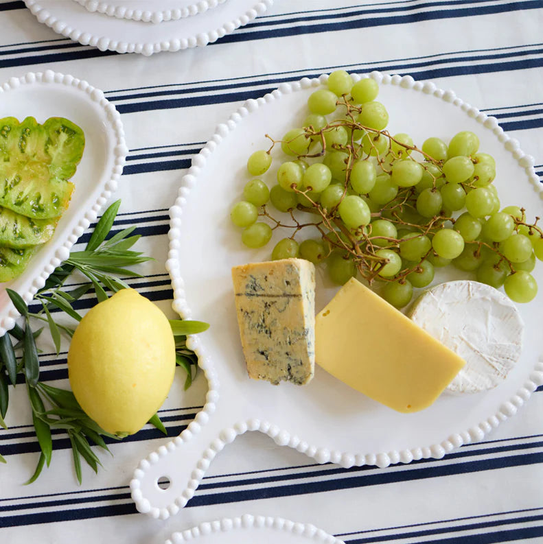 White ceramic platter set on a stripped table cloth with an assortment of foods