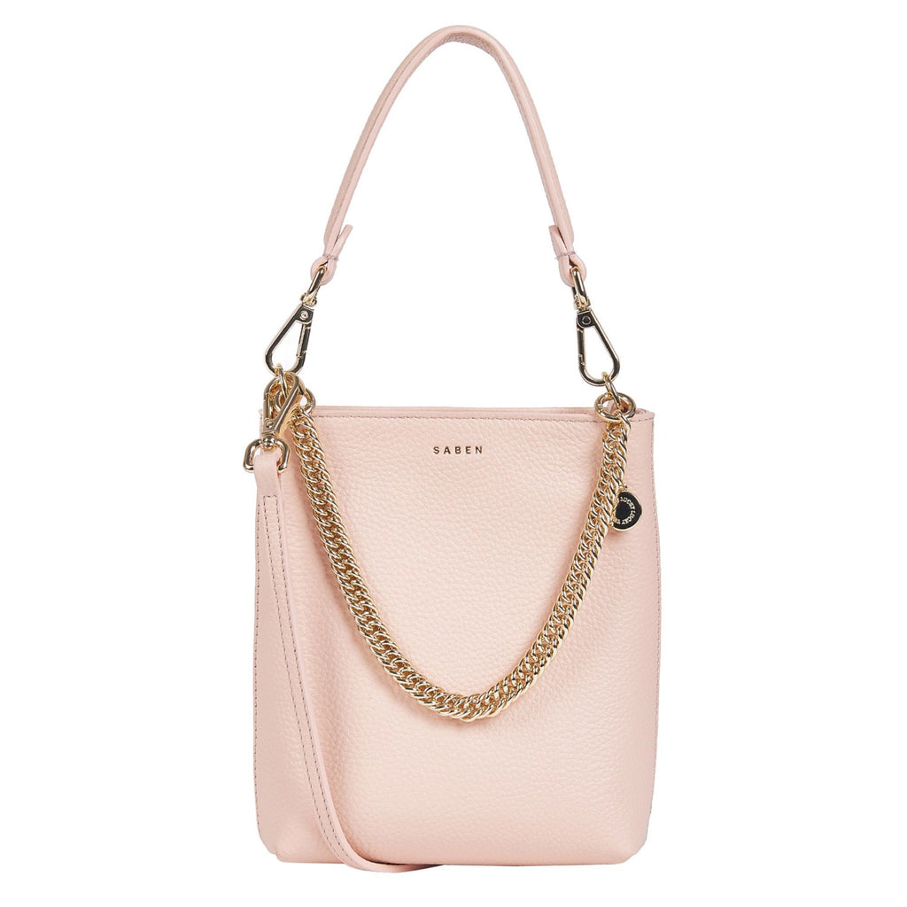 A white background with a blush pink rectangle leather bag featuring a hand strap, gold chain detail across the front and embossed SABEN branding on the front. 