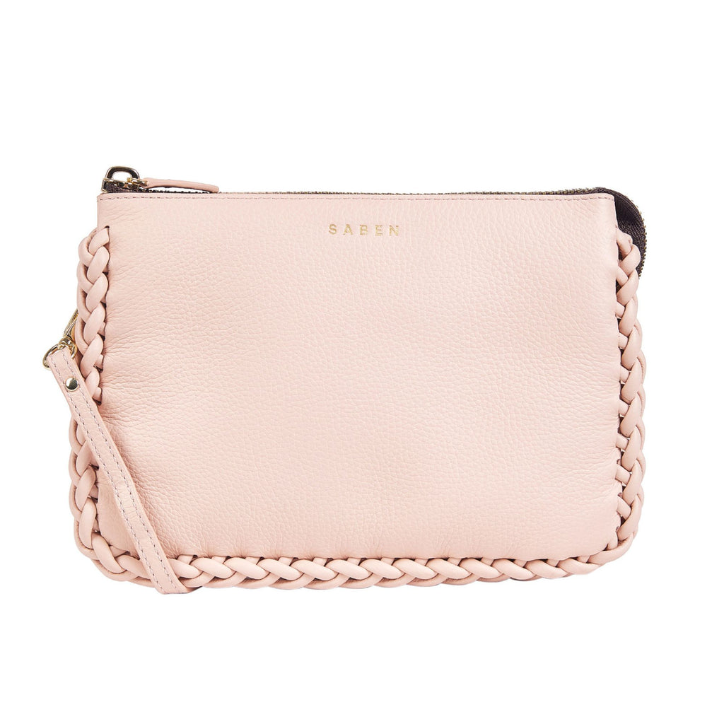 A white background with a blush pink rectangle leather bag with a braided leatheredge, top gold zip opening, and embossed SABEN branding on the front. 