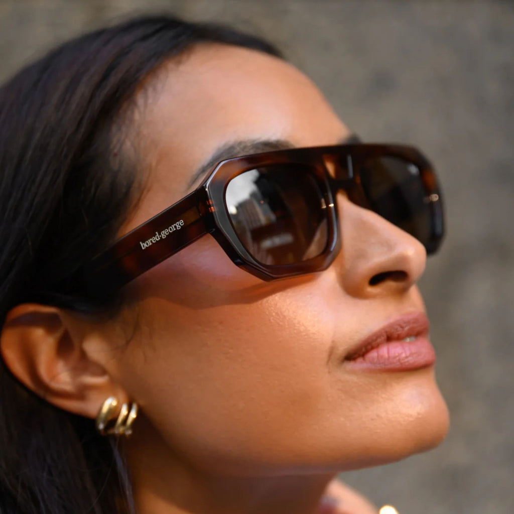 A woman looking on from her side wearing brown sunglasses