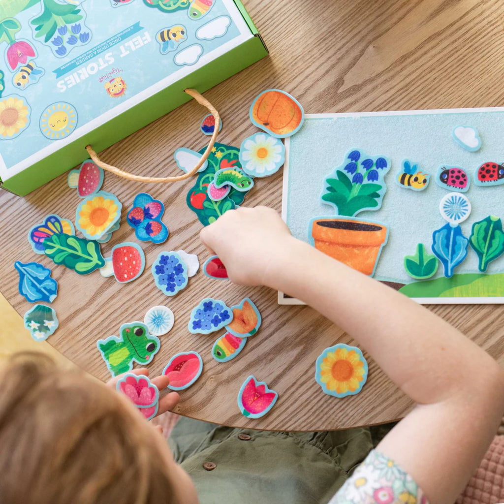 A child playing at a table with a felt board set with garden figures