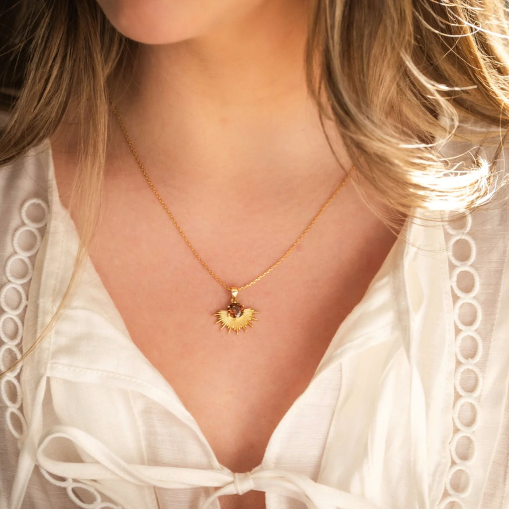 Women wearing gold necklace with brown stone