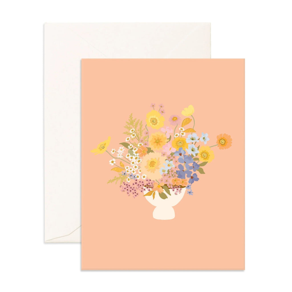 Light pink greeting card with flowers and foliage in a vase on with an envelope