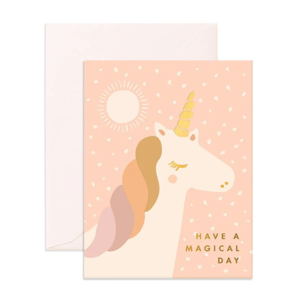 Light pink greeting card with a unicorn, white flecks a and a sun stating "Have a magical day" in gold text with an envelope