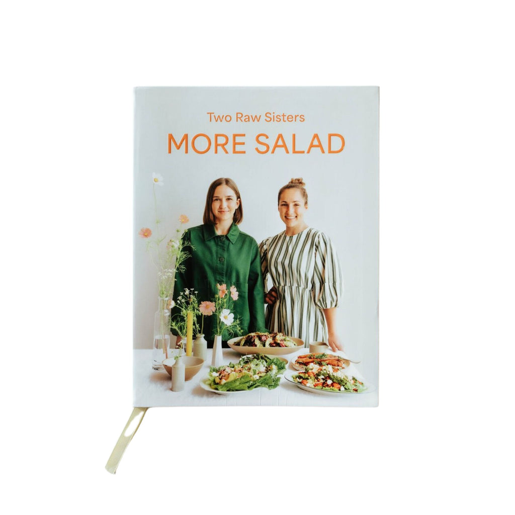 Cook book titled "Two Raw Sisters More Salad" with two girls and na assortment of salads on the front