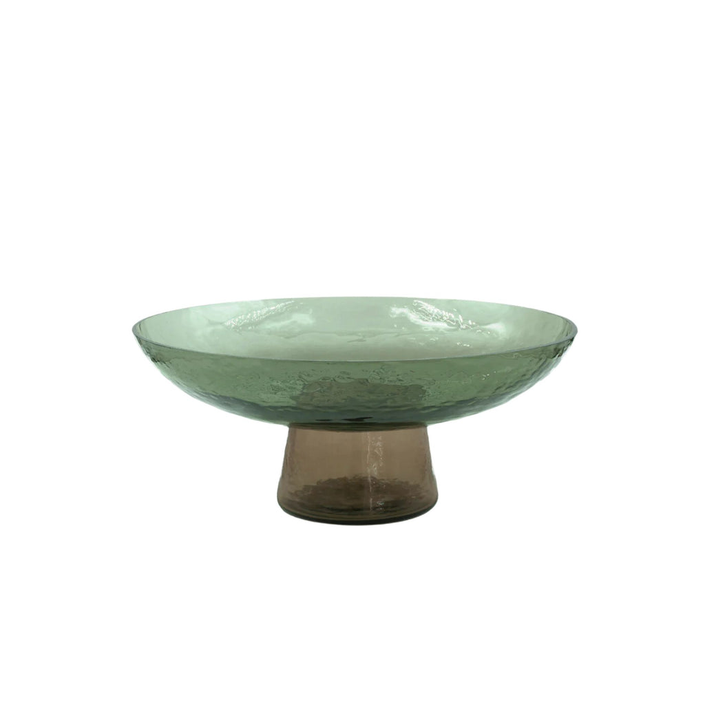 A hammered texture green glass on a bowl on a brown glass stand against a white background