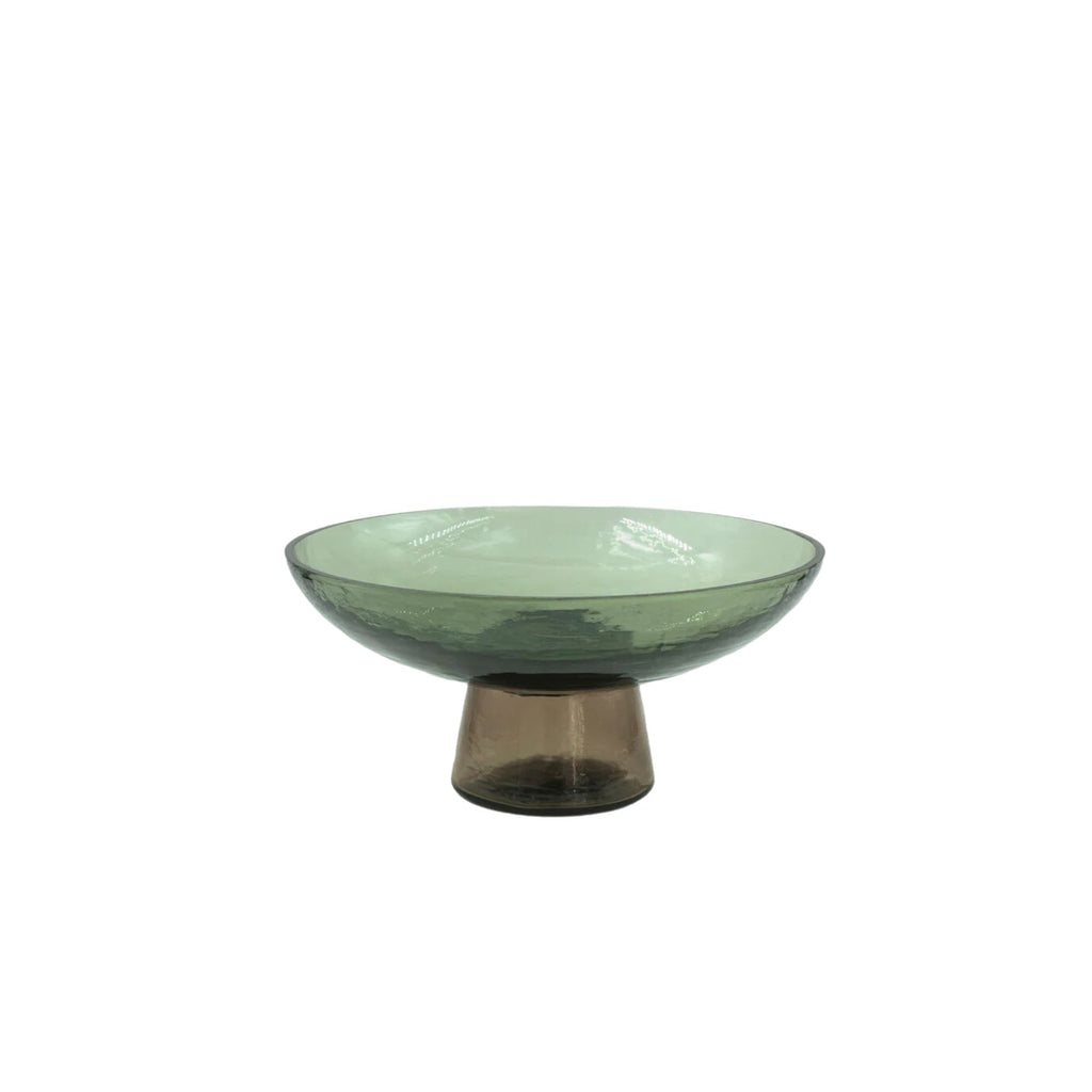 A hammered texture green glass on a bowl on a brown glass stand against a white background