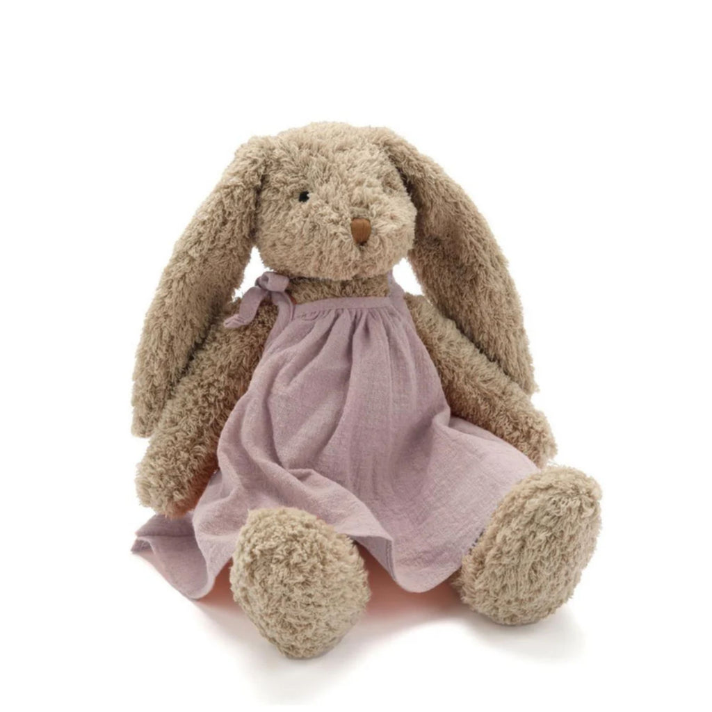 A beige stuffed toy rabbit in a pink linen dress sitting against a white background