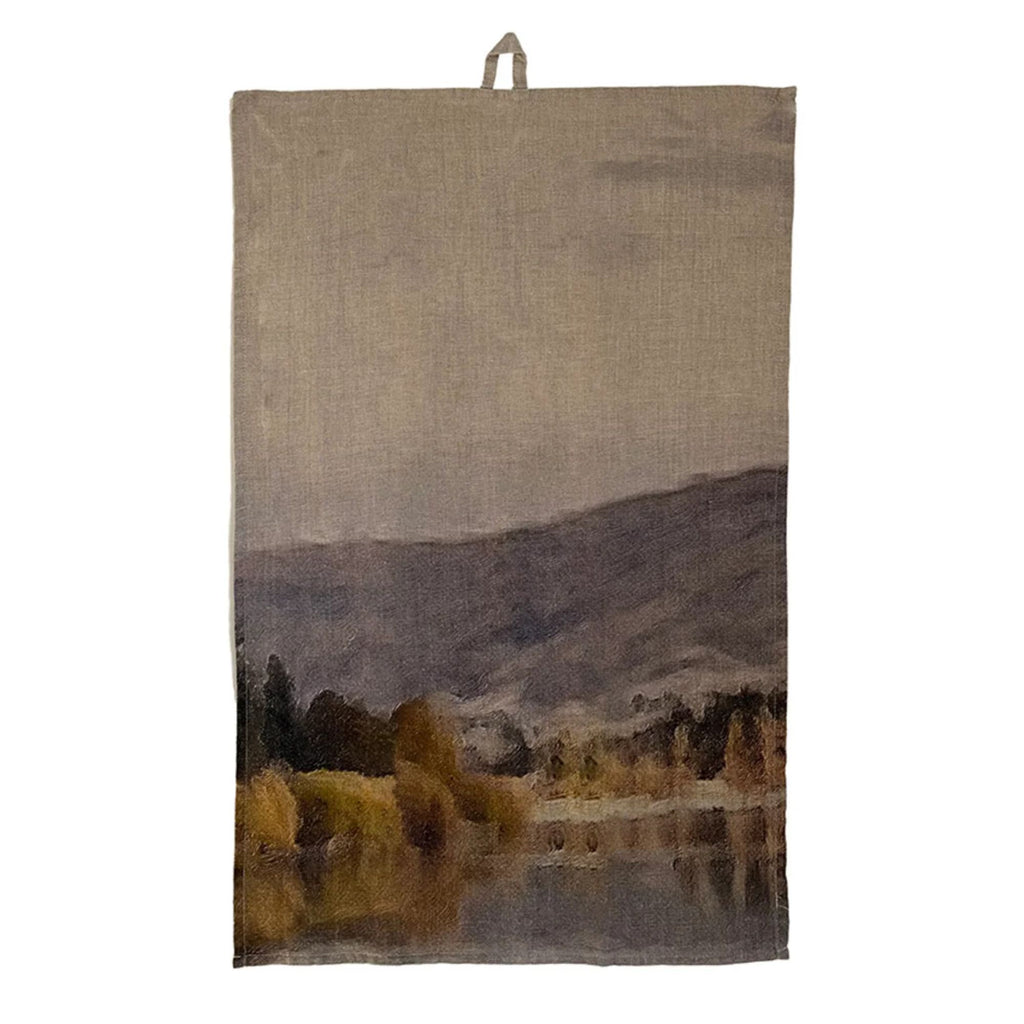 A tea towel with a dark painted landscape on it