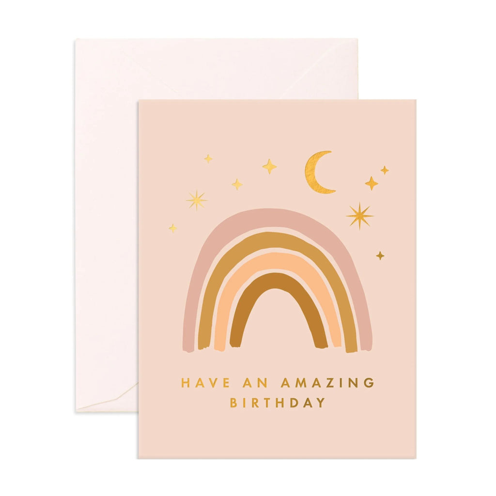 Light pink greeting card with a rainbow, stars and moon stating "have an amazing birthday" in gold text