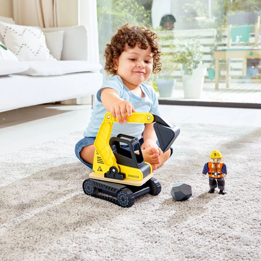 Boy playing with toy excavator, figure and rock