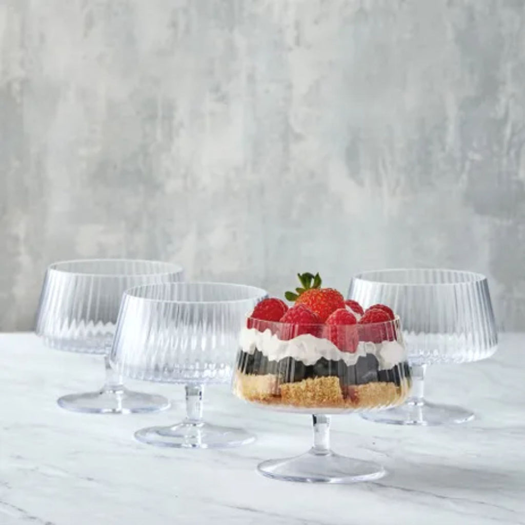 Set of four ribbed glass bowls on stands, with one filled with trifle