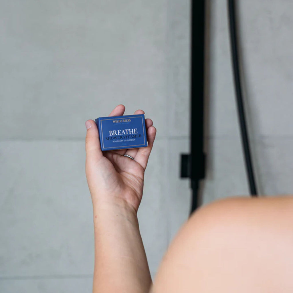 Person in shower holding a shower steamer box in scent breathe