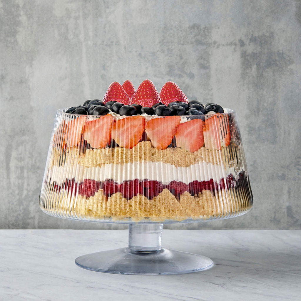 Transparent glass ribbed trifle bowl on a stand filled with trifle