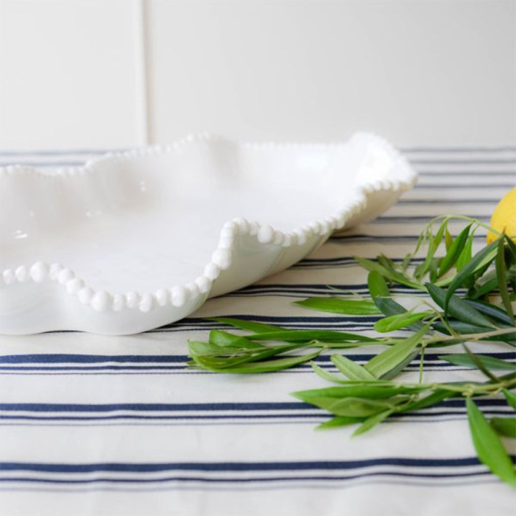 White ceramic serving dish on a striped table cloth with foliage 