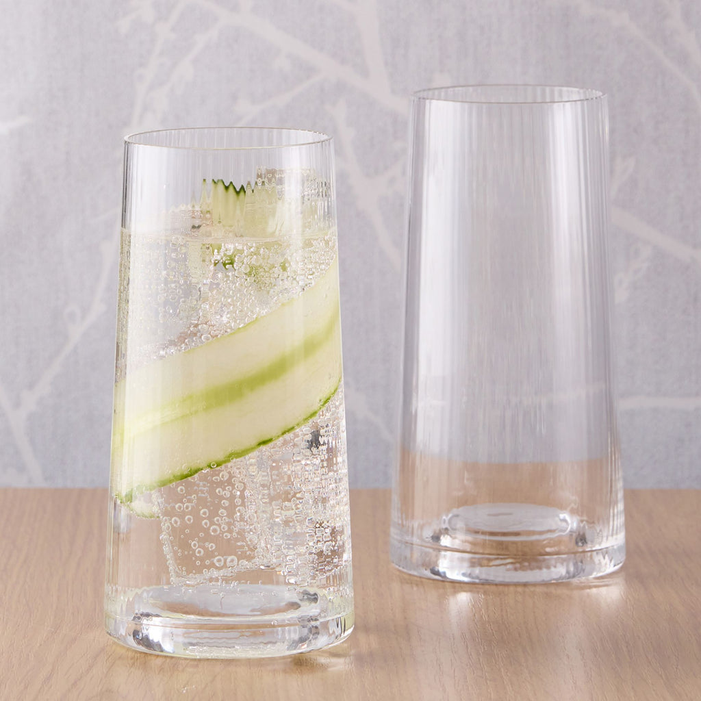 Ribbed highball set of two glasses with one filled with soda and cucumber