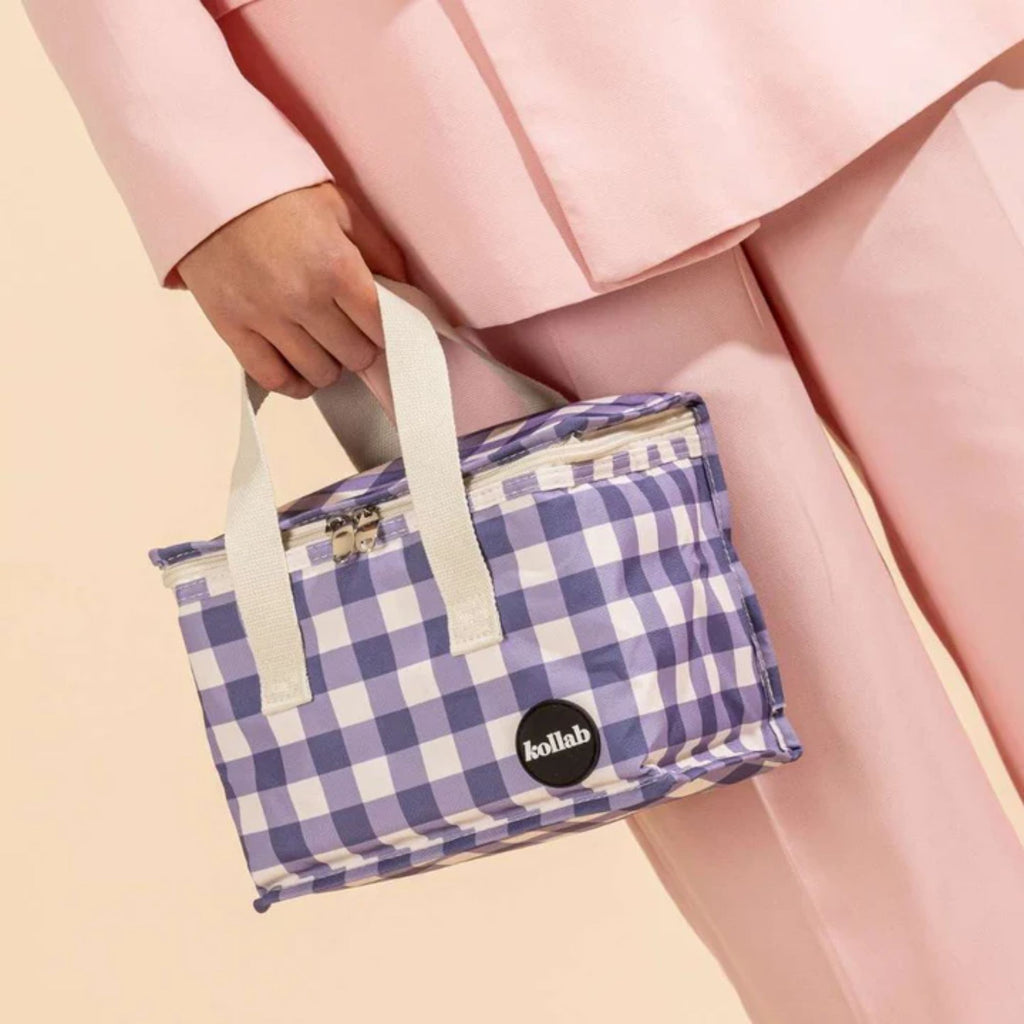 Women wearing pink holding a zipped up Light purple and white checked lunch box with white straps and kollab branding