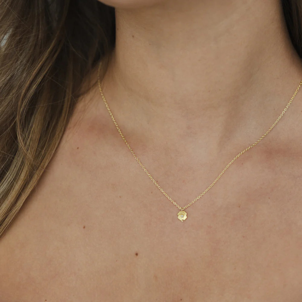 Girl wearing a gold Necklace with a flower pendant and pearl centre