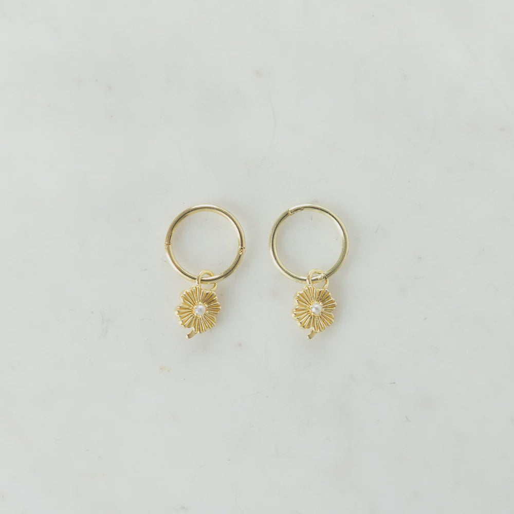 Gold sleeper earrings with a flower pendant and pearl centre